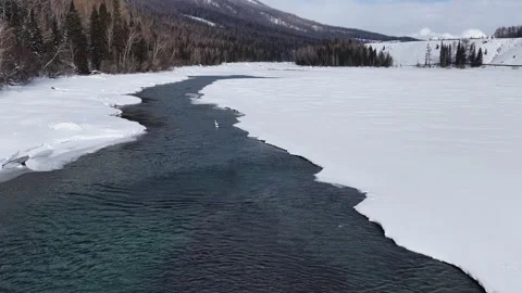Aerial view of clear river in snowy mountain valley in Xinjiang Stock Footage 336609258