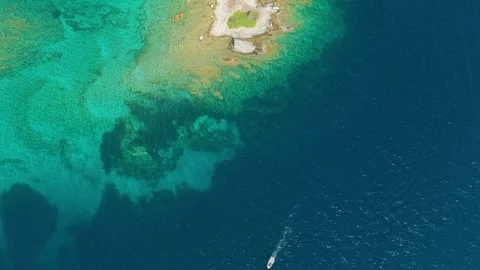 Aerial view of the clear turquoise waters and rocky shoreline of Diaporos Island Stock Footage 346717234