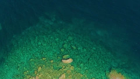 Aerial view of the clear turquoise waters and rocky shoreline of Diaporos Island Stock Footage 346718015