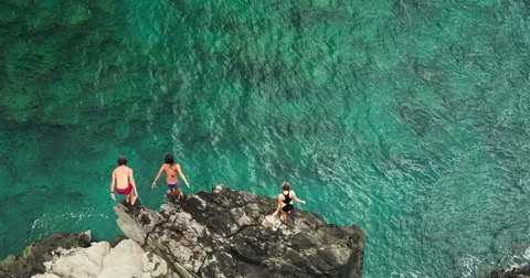 Aerial view cliff jumping into ocean Stock Footage