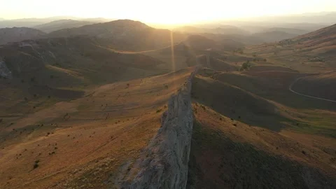Aerial view of cliffs mountains and road at sunset 2 Stock Footage 294103325
