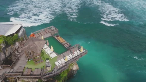 Aerial view of cliffside pool deck above turquoise ocean at Uluwatu, Bali Stock Footage 326589841