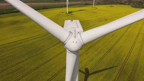 Aerial view close up of wind turbine propeller blades in yellow canola field Stock Footage 75473255
