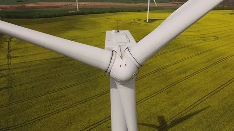 Aerial view close up of wind turbine propeller blades in yellow canola field Stock Footage 75473286