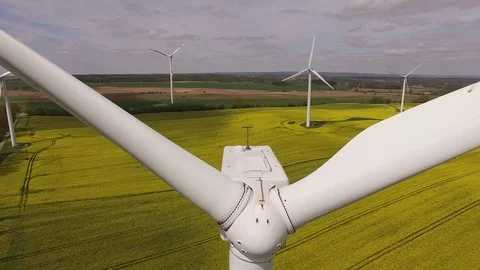 Aerial view close up of wind turbine propeller blades in yellow canola field Stock Footage 75473778