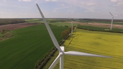 Aerial view close up of wind turbine propeller blades in yellow canola field Stock Footage 75475113