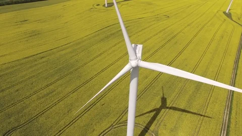 Aerial view close up of wind turbine propeller blades in yellow canola field Stock Footage 75475656