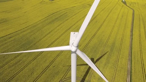 Aerial view close up of wind turbine propeller blades in yellow canola field Stock Footage 75475689