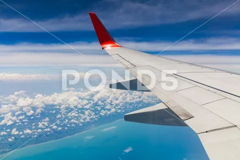 Aerial view of cloud blue sky and plane wing view through the airplane window. Stock Photos