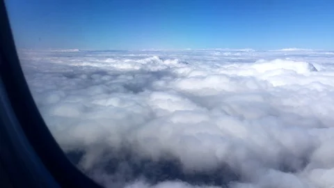Aerial view clouds and blue sky as seen through window of an airplane. 4K 스톡 동영상 105097386