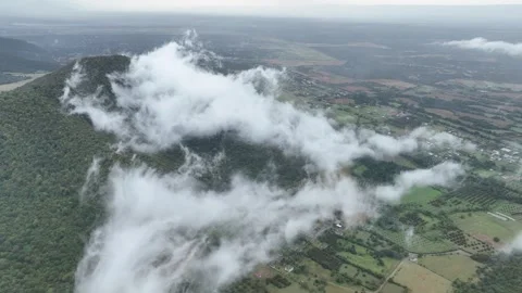 Aerial view of clouds and mist move slowly over a lush green mountain Stock Footage 341904895