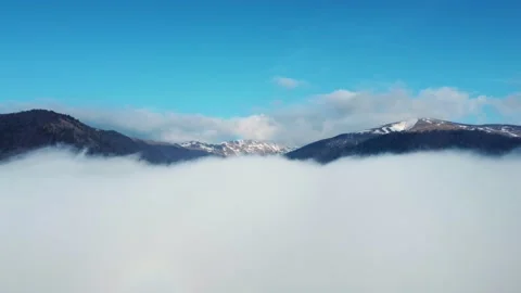 Aerial view of clouds and mountains in the background in the winter time Stock Footage 234640880