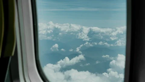 Aerial View of Clouds and Mountains Framed Through Airplane Window Video stock 337948585