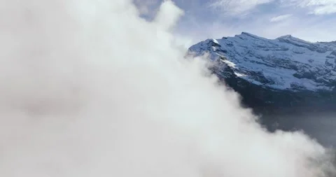 Aerial view of the clouds, rocky mountains are visible through them. Stock Footage 238965734
