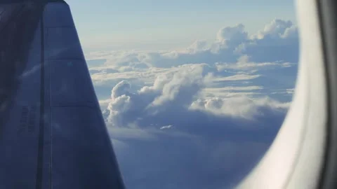 Aerial view of a cloudscape at sunrise through an airplane window. Airplane Stock Footage 321757052