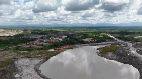 An aerial view of a coal mine pit filled with mud and surrounded by oil pal.. 動画素材 343249208