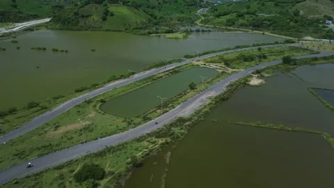 Aerial View Of Coastal Causeway Navigating Salt Flats And Pond Networks 動画素材 334337732