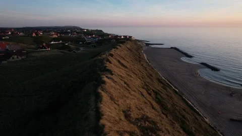 Aerial View of Coastal Cliffs, Beach and Seaside Village at Sunset Stock Footage 343521081