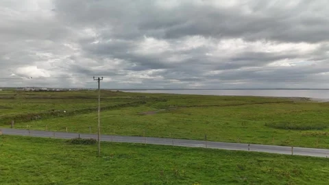 Aerial view of coastal fields road and power lines under cloudy sky Stockbeeldmateriaal 332679827