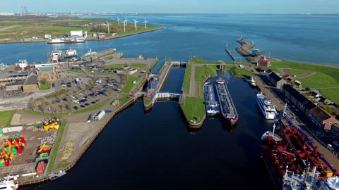 Aerial view of a coastal harbor with a lock system, docked vessels, parking Stock Footage 336744630