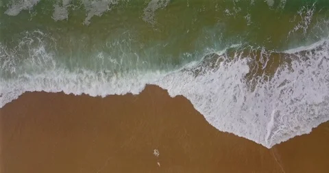 Aerial view of a coastal section with approaching breaking waves and spray Stock Footage