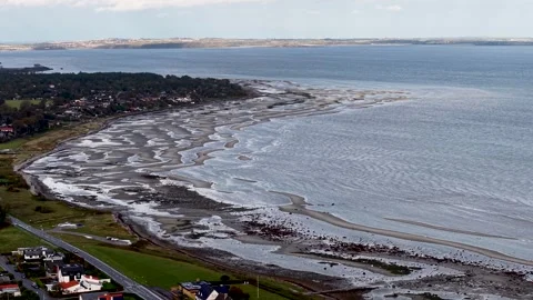 Aerial view of a coastline with low tide revealing sandy patterns and small Stock Footage 337138602