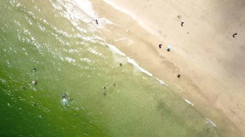 Aerial view of the coastline with people standing in the water Stock Photos