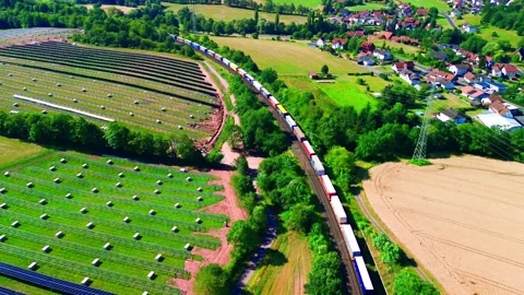 Aerial view of a colourful container freight train passing a large hillside Stockbeeldmateriaal 342246708