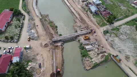 Aerial view of the construction site of a bridge over the river Stock Footage 294979319