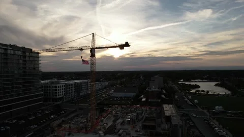 Aerial view of construction site with crane and American flag at sunset Stock Footage 345442615