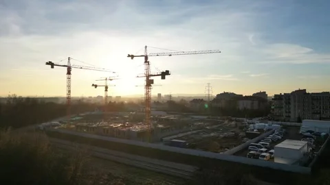Aerial view to construction site illuminated by sunset, featuring cranes and Vidéo 335886927