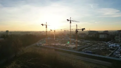 Aerial view to construction site illuminated by sunset, featuring cranes and Stock Footage 335886968
