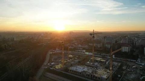 Aerial view to construction site illuminated by sunset, featuring cranes and 库存影片 335887018