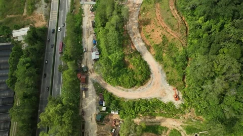 Aerial View of Construction Site Surrounded by Lush Greenery and Roadway Stock Footage 316450410
