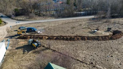Aerial view of construction workers digging a trench in a field Stock Photos