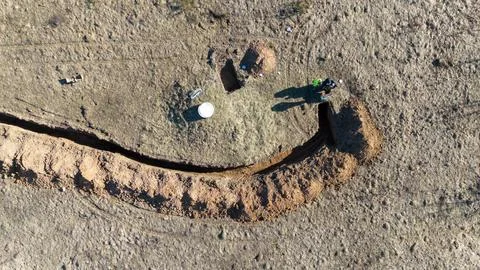 Aerial view of construction workers digging a trench in a field Stock Photos