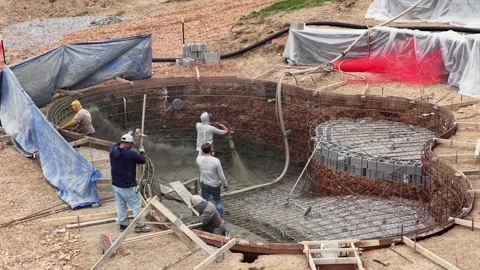 Aerial view of construction workers spraying gunite into backyard swimming pool Stock Footage 333398871