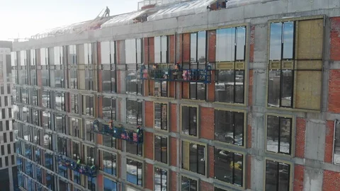 Aerial view to the construction works on a skyscraper wall on a sunny winter day Stock Footage 120148437