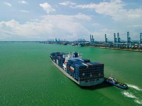Aerial view of container ship sailing near a busy cargo port. Stock-Fotos