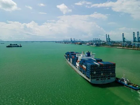 Aerial view of container ship sailing near a busy cargo port. Fotos de archivo