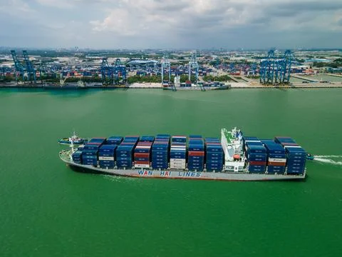 Aerial view of container ship sailing near a busy cargo port Foto stock