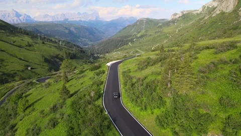 An aerial view of a convertible driving through the Alpine scenery Stock Footage 274913136