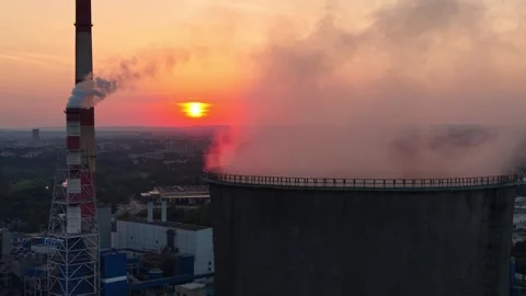 Aerial view of cooling tower emitting steam against a vibrant sunset Stock Footage 337909656