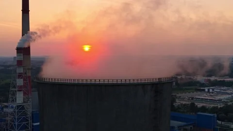 Aerial view of cooling tower emitting steam against a vibrant sunset, with the Stock Footage 341473492