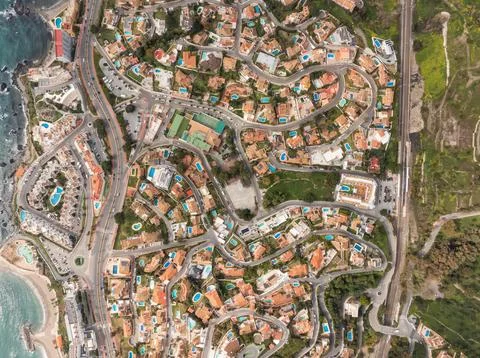 Aerial view of Costa del Sol streets, villas, and pools by rocky coast Stock Photos