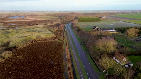 Aerial view of a countryside road, bordered by fields, trees, and houses. Stock Footage 299298596