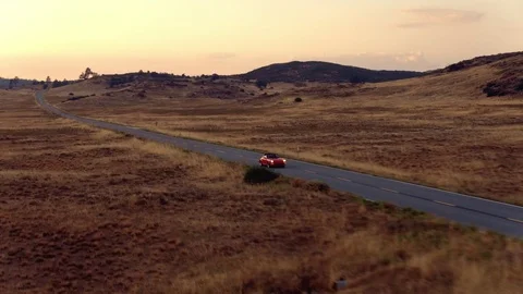 Aerial View Of Couple Driving Red Coverable Sports Car Down Country Road At Dusk Stock Footage