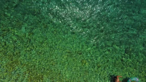 Aerial view of couple floating in crystal clear sea water Stockbeeldmateriaal 340181992