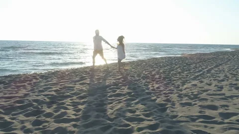 Aerial view of couple having fun running along the beach near the water Stock Footage 118538502
