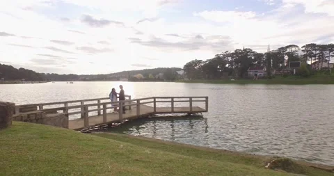 Aerial view a couple at small dock in beautiful Xuan Huong lake at sunrise Stock Footage 130896225